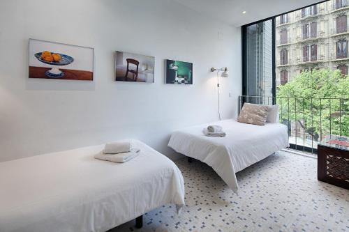バルセロナにあるHabitat Apartments Pedreraの白い部屋で、ベッド2台、窓が備わります。