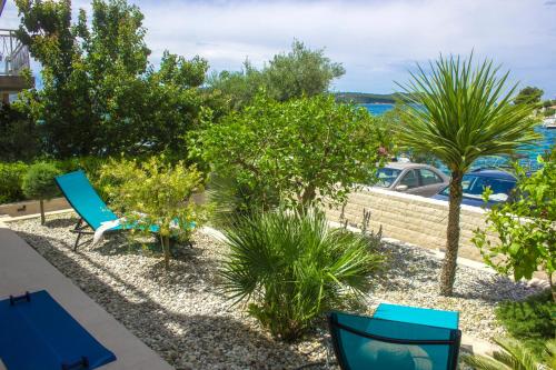 eine Terrasse mit blauen Stühlen, Bäumen und Wasser in der Unterkunft Villa Vala in Zaboric