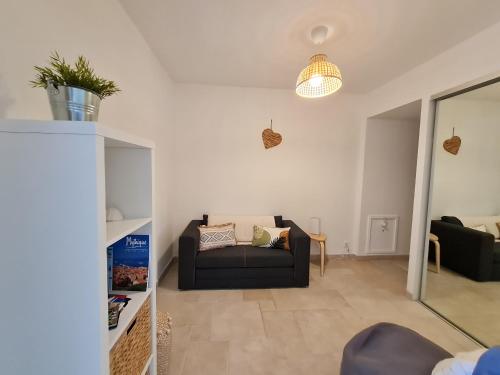 a living room with a black couch and a table at Bel appartement rénové, avec terrasse et piscine in La Croix-Valmer