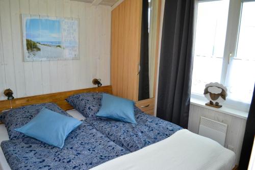 Un dormitorio con una cama con almohadas azules y una ventana en Modernes Ferienhaus direkt an der Nordsee, en Wesselburenerkoog