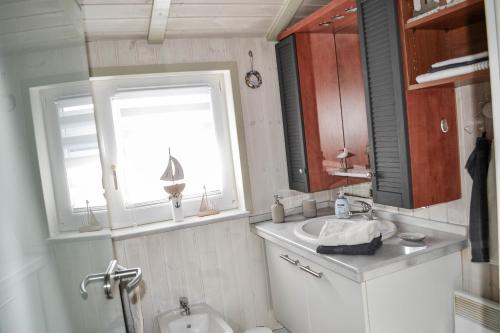 La salle de bains est pourvue d'un lavabo, de toilettes et d'une fenêtre. dans l'établissement Modernes Ferienhaus direkt an der Nordsee, à Wesselburenerkoog