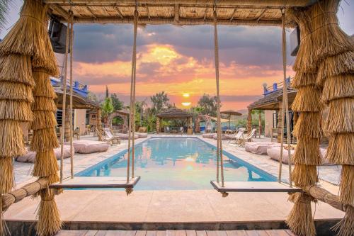 a pool at a resort with a sunset at La Fattoria Ecolodge in Lalla Takerkoust