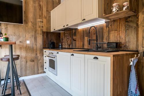a kitchen with white cabinets and wooden walls at Domandi mountain holiday lodges in Przesieka