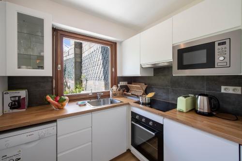 une cuisine avec des armoires blanches, un évier et une fenêtre dans l'établissement Apt du Brévent ski in ski out - Happy Rentals, à Chamonix-Mont-Blanc