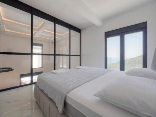 a white bedroom with a large bed and large windows at Seaview Villa with pool-Vanja in Budva