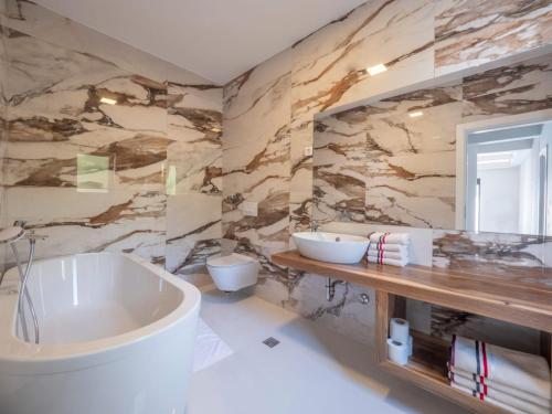 a bathroom with a large tub and a stone wall at Seaview Villa with pool-Vanja in Budva