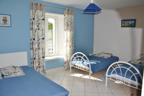 Habitación azul con 2 camas y ventana en La rosiere en Touligny