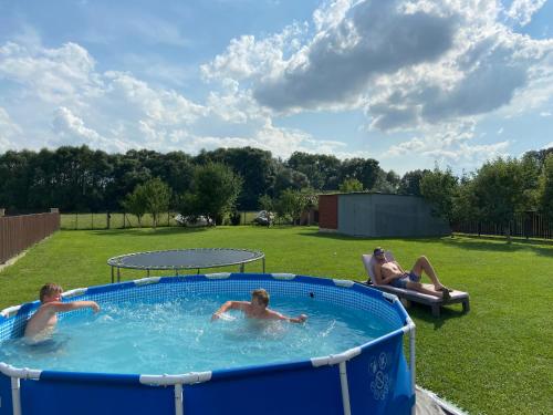 three people swimming in a pool in a yard at Apartament Vanessa 2 u podnóża gór, nad jeziorem Czorsztyńskim in Harklowa