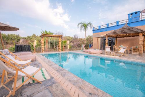 a swimming pool with chairs and a house at La Fattoria Ecolodge in Lalla Takerkoust