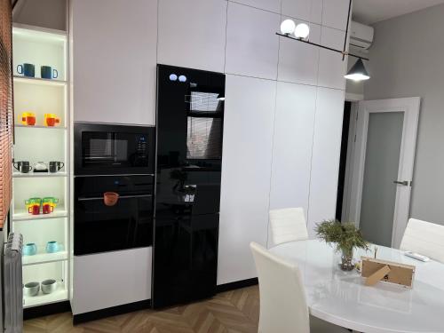 a kitchen with a table and a black and white refrigerator at Brand new one bedroom apartment with amazing view in Bishkek