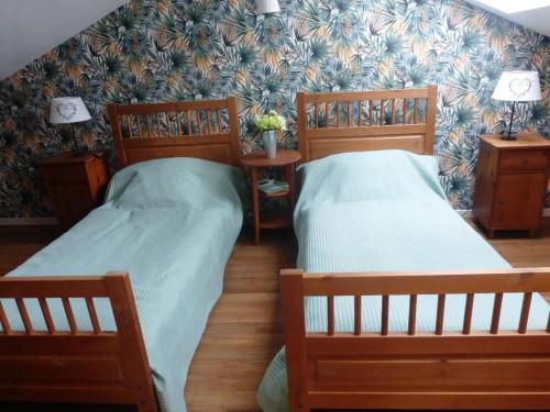 duas camas num quarto com duas lâmpadas e uma parede em La beuquette 