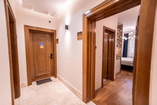 a hallway with wooden doors and tile floors at Studio 106 Apartment in Palić
