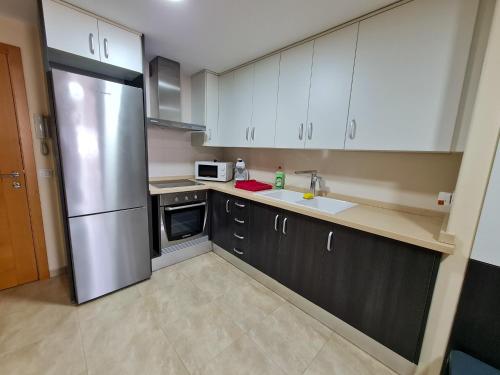 a kitchen with white cabinets and a stainless steel refrigerator at Las Jarcias in Moncófar