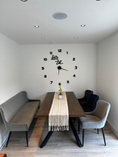 mesa de comedor con sillas y reloj en la pared en Luxury West London 3BR House, Cul De Sac, en Isleworth