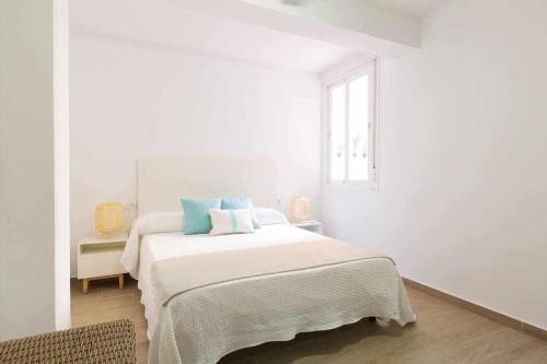 een witte slaapkamer met een groot bed met blauwe kussens bij Luna de Málaga in Málaga