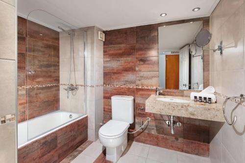 een badkamer met een toilet, een bad en een wastafel bij Aeolian Village Beach Resort in Skala Eresou