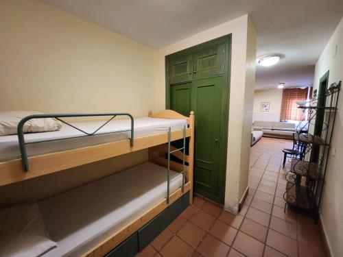 シエラネバダにあるdornajo en la plazaの二段ベッド2台と緑のドアが備わる客室です。