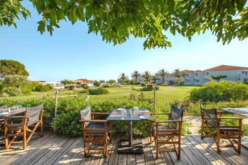 a table and chairs on a deck with a view of a field at Aeolian Village Beach Resort in Skala Eresou