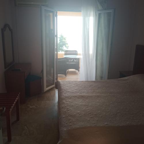 a bedroom with a bed and a window with a piano at Niki Sunrise Apartments in Gastourion