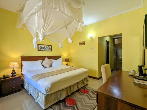 a bedroom with a large bed with a desk and a desk at Mvuli Hotels Arusha in Arusha