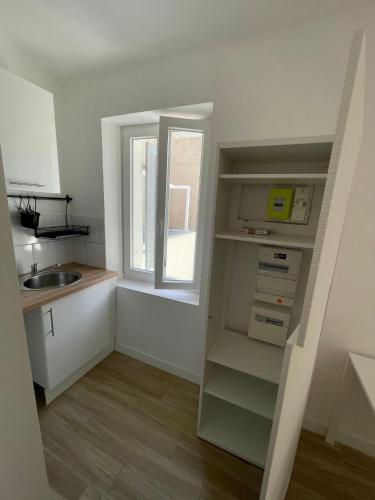 une petite cuisine avec un évier et une fenêtre dans l'établissement joli appartement plein sud 15mn des plages et wifi gratuit, à Marseille