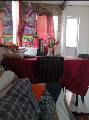mesa de comedor con mantel rojo y árbol de Navidad en Island Princess Guesthouse, en Puerto Princesa City