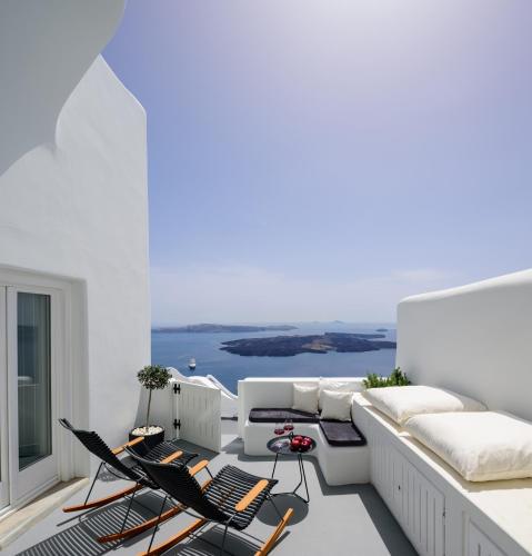 a balcony with white furniture and a view of the ocean at Aethria Villa in Imerovigli