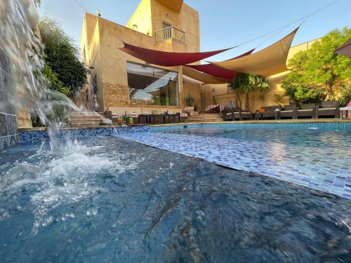a swimming pool with a fountain in front of a building at Orient Villa-Dead Sea in Sowayma