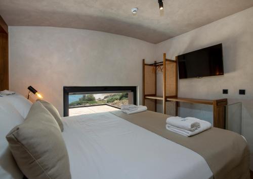 a bedroom with a large white bed and a television at Balos Beach in Kissamos