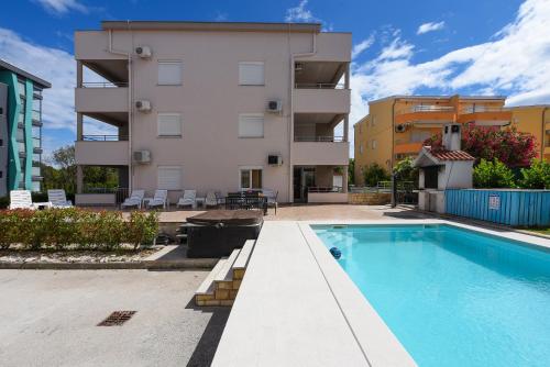 an apartment with a swimming pool in front of a building at Sunset Beach Suites in Kožino