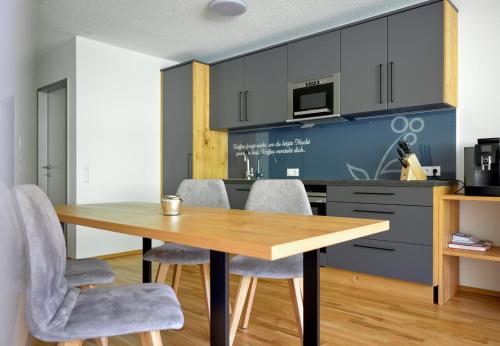 a kitchen with a wooden table and gray chairs at Zapfig Living Arlberg in Wald am Arlberg
