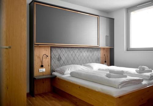 a bedroom with two beds with a large screen on the wall at Zapfig Living Arlberg in Wald am Arlberg