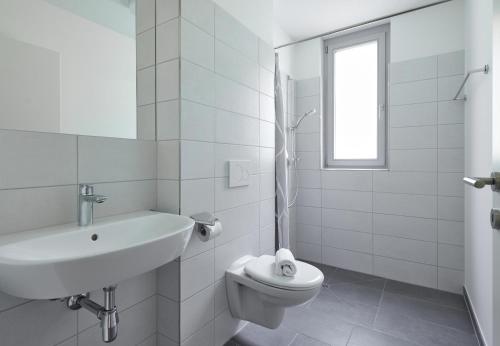 a white bathroom with a sink and a toilet at Zapfig Living Arlberg in Wald am Arlberg