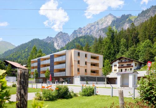 a large building with mountains in the background at Zapfig Living Arlberg in Wald am Arlberg