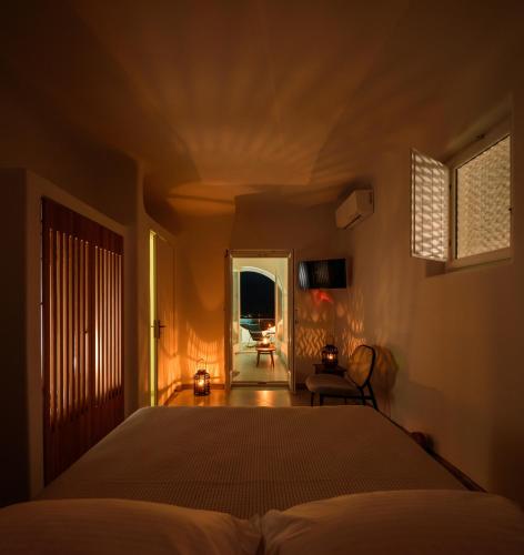 a bedroom with a bed and a window and a chair at Aethria Villa in Imerovigli