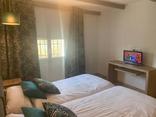 een slaapkamer met een bed en een tv aan de muur bij Provencelia in Pernes-les-Fontaines