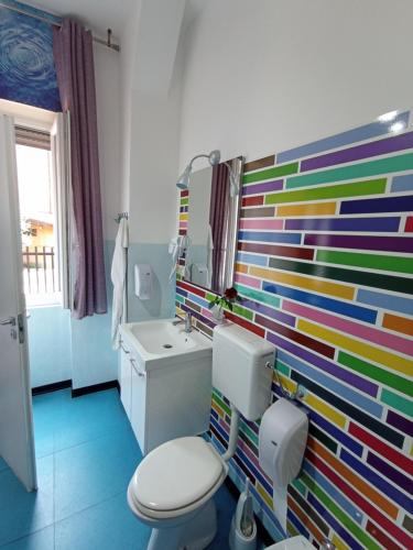 a bathroom with a colorful wall with a toilet and sink at Milano Ostello in Milan