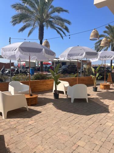 a group of white chairs and umbrellas on a patio at Hotel Jolly Roger in Pietra Ligure