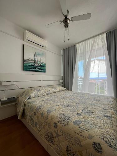 a bedroom with a bed and a large window at Apartmani Mira Sumić in Podgora