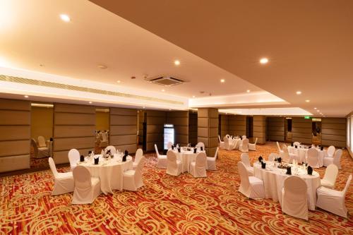 um salão de banquetes com mesas e cadeiras brancas em Courtyard by Marriott Pune Chakan em Chākan