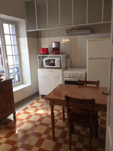a kitchen with a table and a microwave and a refrigerator at Le capucin in Le Mont-Dore