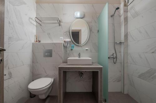 a bathroom with a sink and a toilet and a mirror at Sunshine Apartments in Neos Marmaras