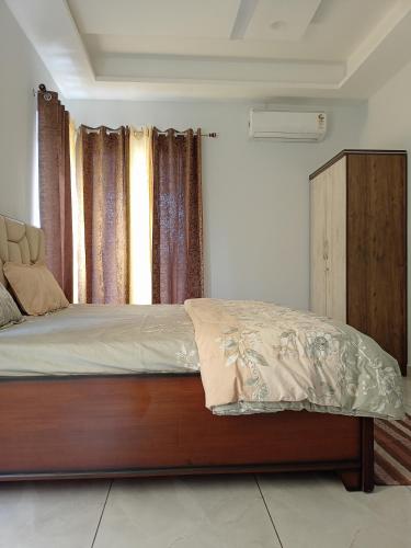 a bedroom with a bed and a window with curtains at Ananta - Rishikesh Luxurious 2BHK in Rishīkesh