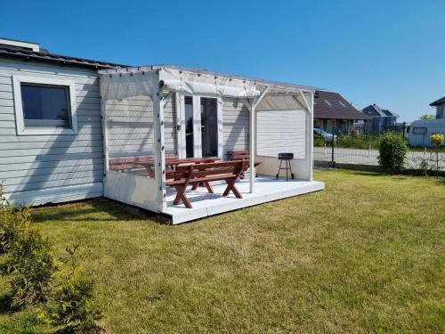 a house with a picnic bench in the yard at 365PAM - Domek Letniskowy Kolory Lata - Z KLIMATYZACJĄ I PARKINGIEM in Sarbinowo