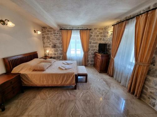 a bedroom with a bed and a television and curtains at Palace Jelena Rooms in Perast