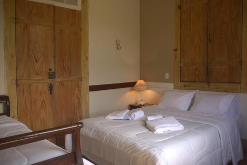 um quarto com uma cama branca e toalhas em FAZENDAS ANTIGAS HOTEL em Sumidouro
