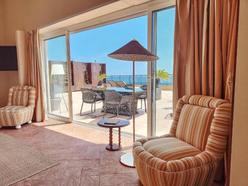 a living room with a table and chairs and a balcony at Hôtel La Pérouse Nice Baie des Anges in Nice