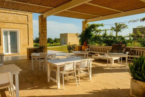 a patio with tables and chairs and a bench at Residenza Case Arse in Torre Lapillo