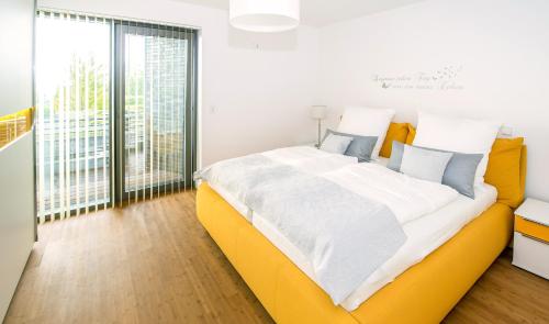 Cama amarilla grande en habitación con ventana grande en Ferienwohnung Glücksburg, en Twedterholz