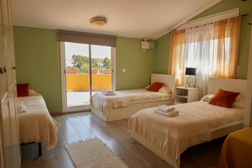 OlivellaにあるAmazing Vila close to Sitges, jacuzzi, swimming pool & exellent viewsのベッドルーム1室(ベッド2台、大きな窓付)
